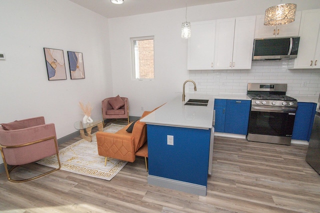 kitchen featuring white cabinets, appliances with stainless steel finishes, a peninsula, light countertops, and a sink