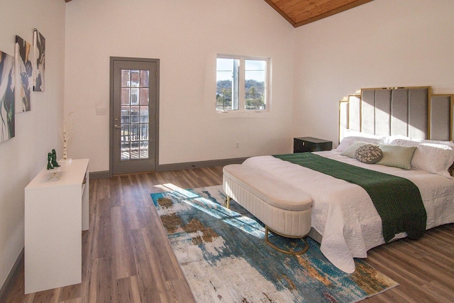 bedroom featuring lofted ceiling, access to outside, wood finished floors, and baseboards