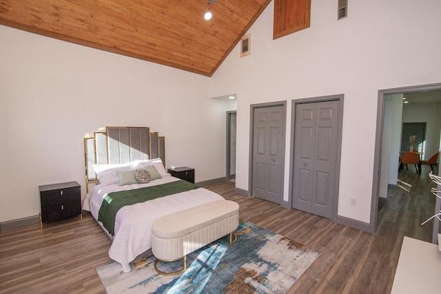 bedroom featuring visible vents, baseboards, wooden ceiling, wood finished floors, and two closets