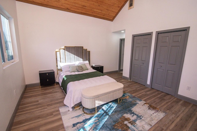 bedroom with wooden ceiling, wood finished floors, visible vents, baseboards, and multiple closets