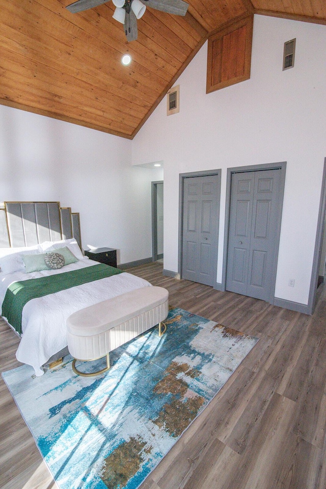 bedroom featuring multiple closets, wooden ceiling, visible vents, and wood finished floors