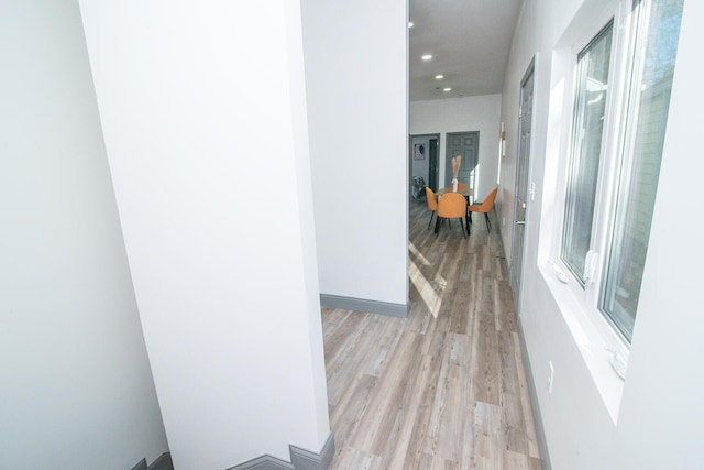 corridor with light wood-type flooring, baseboards, and recessed lighting