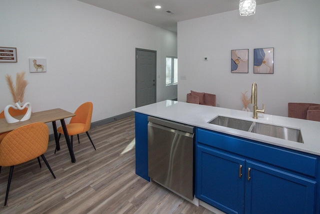 kitchen with blue cabinets, a sink, light countertops, stainless steel dishwasher, and light wood-type flooring