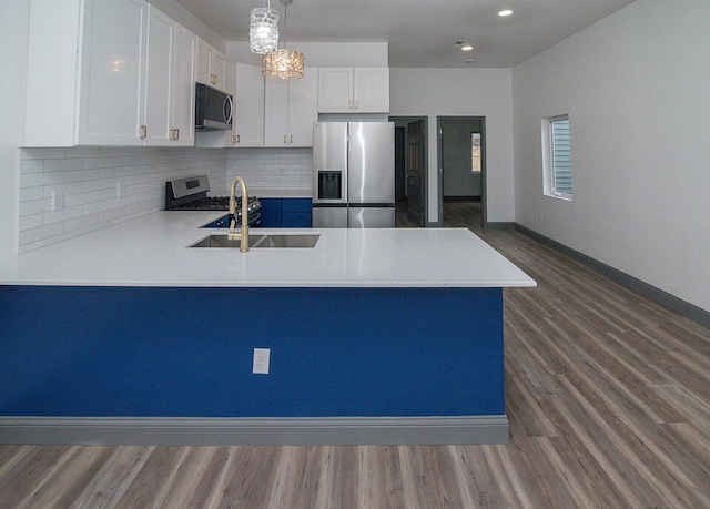 kitchen with baseboards, white cabinets, appliances with stainless steel finishes, a peninsula, and backsplash