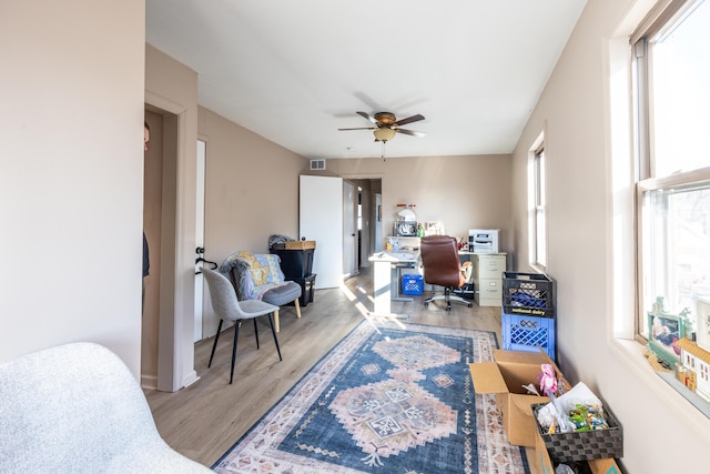 home office featuring visible vents, light wood-type flooring, and ceiling fan