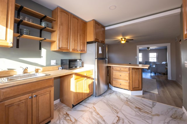 kitchen with brown cabinetry, a peninsula, stainless steel appliances, and a sink