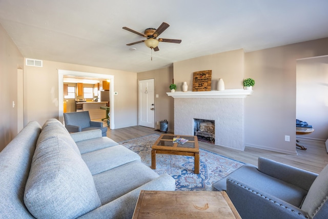 living room with ceiling fan, visible vents, baseboards, and wood finished floors