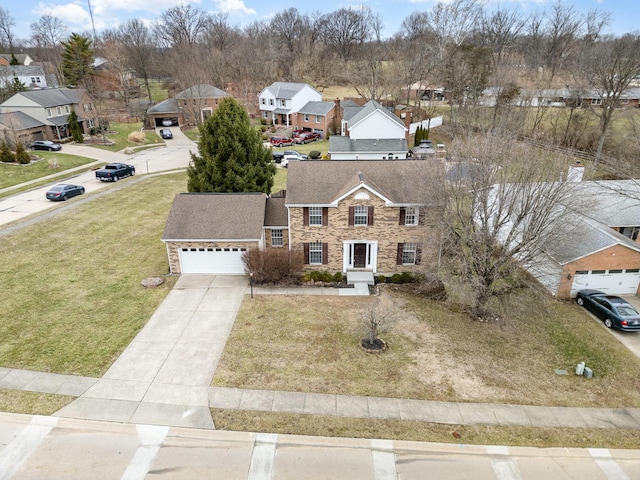 view of front facade with a front yard, concrete driveway, a garage, stone siding, and a residential view