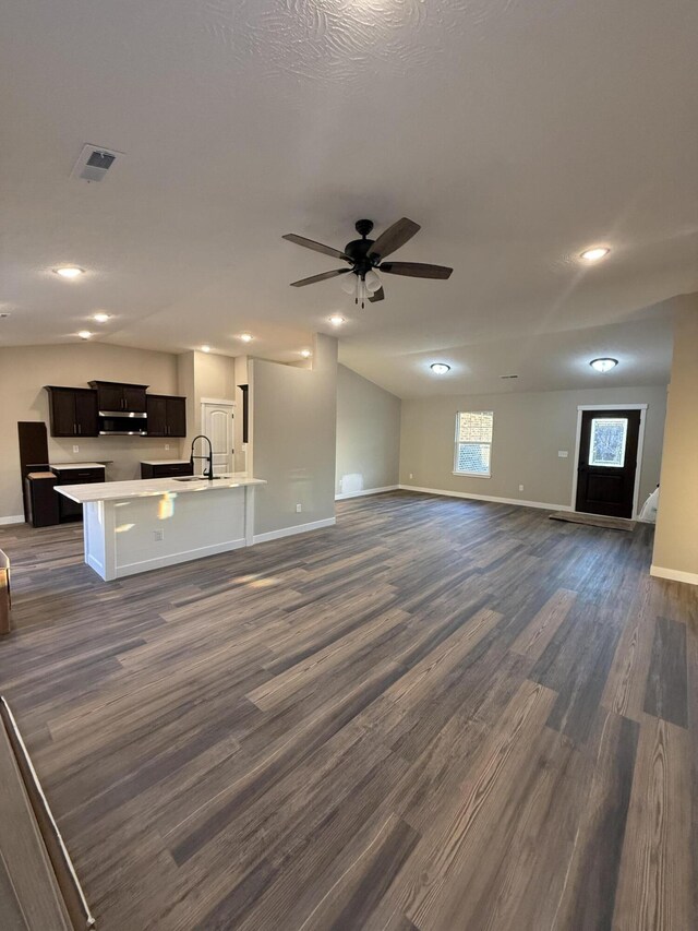 unfurnished living room with a sink, visible vents, baseboards, and dark wood-style floors