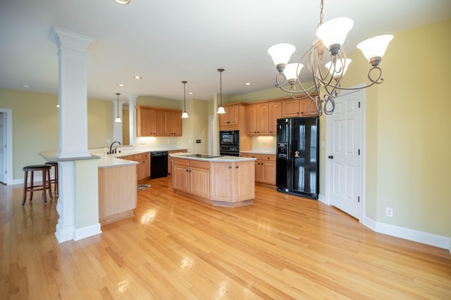 kitchen with baseboards, light wood finished floors, decorative columns, black appliances, and light countertops