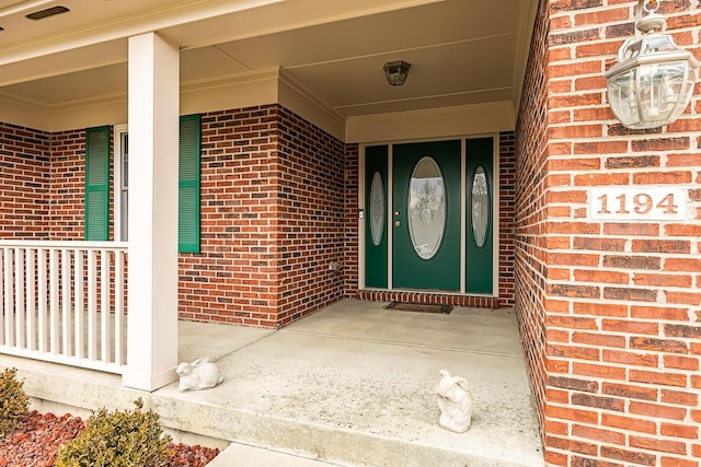 doorway to property featuring brick siding and a porch