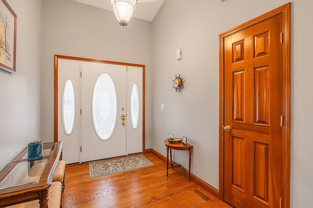 foyer with light wood-type flooring, visible vents, and baseboards