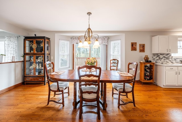 dining space with an inviting chandelier, light wood-style flooring, and baseboards