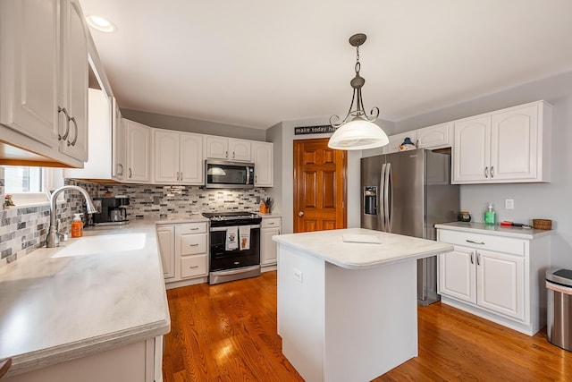 kitchen featuring white cabinetry, appliances with stainless steel finishes, a sink, and wood finished floors