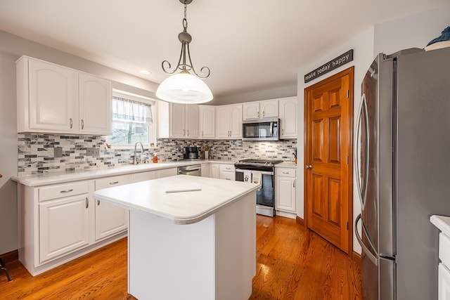 kitchen featuring tasteful backsplash, stainless steel appliances, light countertops, light wood-type flooring, and white cabinetry