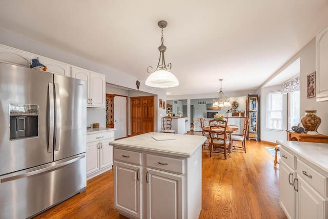 kitchen featuring light countertops, light wood-type flooring, stainless steel fridge, and white cabinets