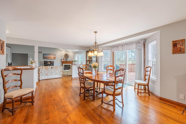 dining room featuring baseboards, a fireplace, visible vents, and wood finished floors