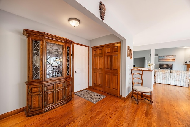 foyer featuring a fireplace, wood finished floors, visible vents, and baseboards