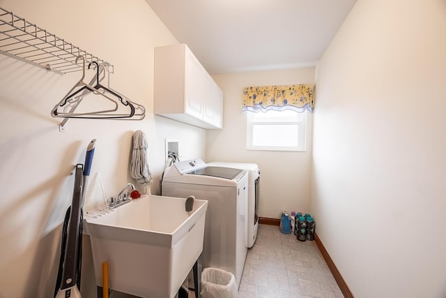 laundry area with cabinet space, washing machine and dryer, baseboards, and a sink