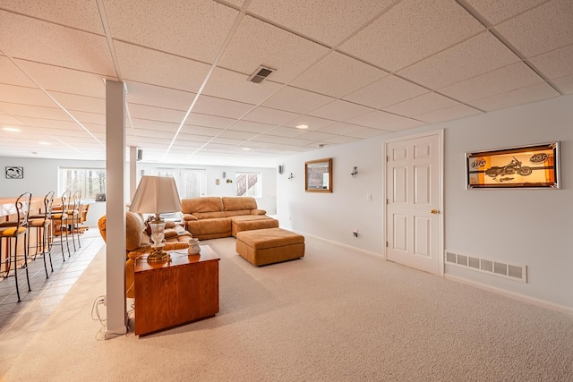 living area with carpet, visible vents, and a paneled ceiling