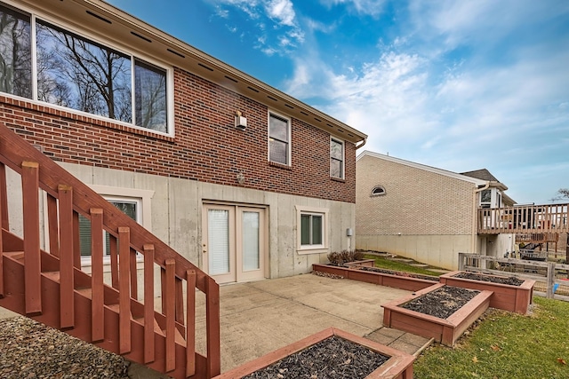 back of property with a patio area, a garden, and brick siding