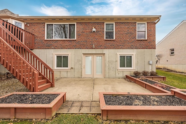 back of property featuring brick siding, a garden, stairway, and a patio