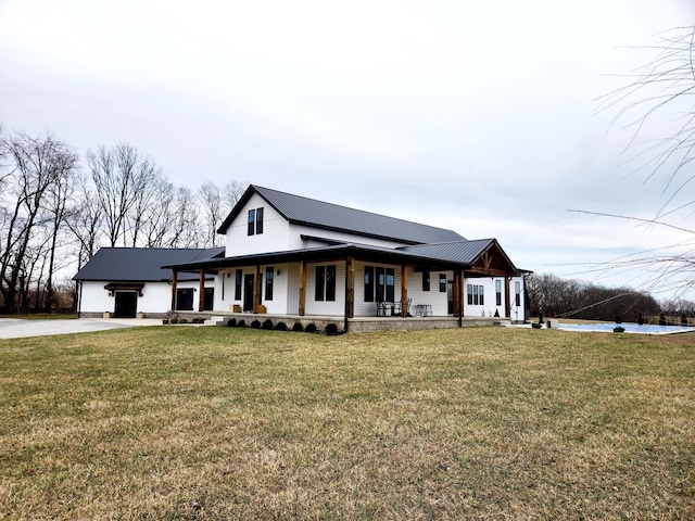 modern inspired farmhouse with a front yard, covered porch, metal roof, driveway, and an attached garage