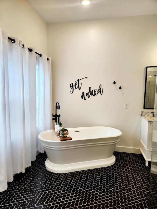 bathroom with vanity, baseboards, and a freestanding tub