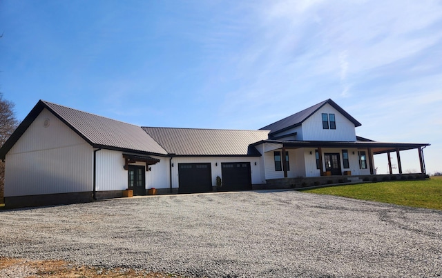 modern farmhouse with driveway, a porch, a front lawn, a garage, and metal roof
