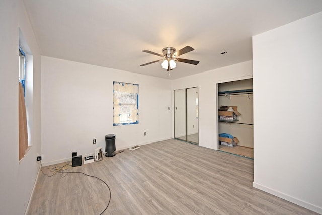 interior space with a ceiling fan, baseboards, two closets, and wood finished floors