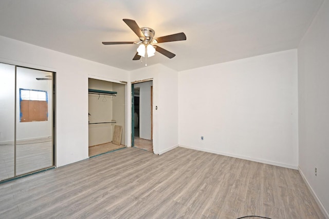 unfurnished bedroom with multiple closets, baseboards, a ceiling fan, and wood finished floors