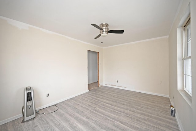 unfurnished room with ornamental molding, light wood finished floors, and baseboards