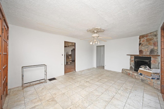 unfurnished living room with ceiling fan, a textured ceiling, and a fireplace