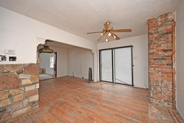 unfurnished living room featuring hardwood / wood-style flooring, a textured ceiling, and a ceiling fan