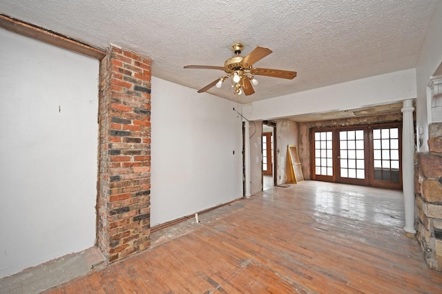 empty room with a textured ceiling, french doors, wood-type flooring, and a ceiling fan