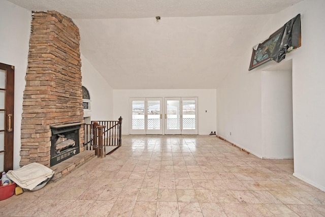 unfurnished living room with a textured ceiling, high vaulted ceiling, a fireplace, baseboards, and french doors