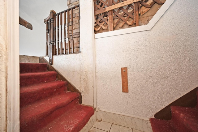 stairs with tile patterned floors and a textured wall