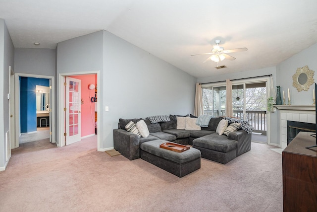 living area featuring carpet flooring, vaulted ceiling, ceiling fan, a tile fireplace, and baseboards