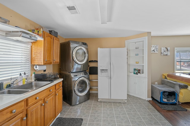 washroom with visible vents, laundry area, a sink, and stacked washer and clothes dryer