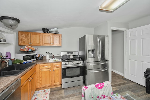 kitchen with appliances with stainless steel finishes, light countertops, a sink, and dark wood-style floors