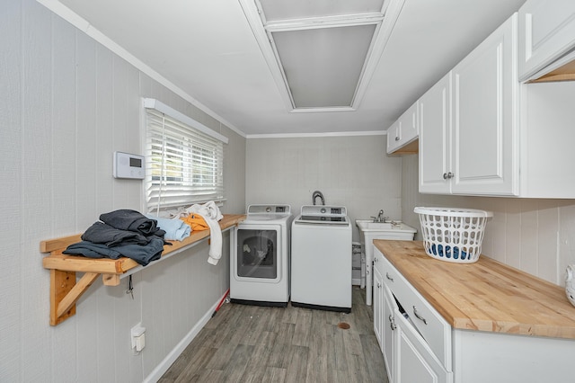 clothes washing area featuring ornamental molding, washer and dryer, cabinet space, and light wood finished floors