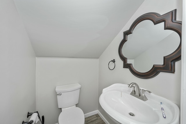 bathroom featuring baseboards, toilet, wood finished floors, vaulted ceiling, and a sink