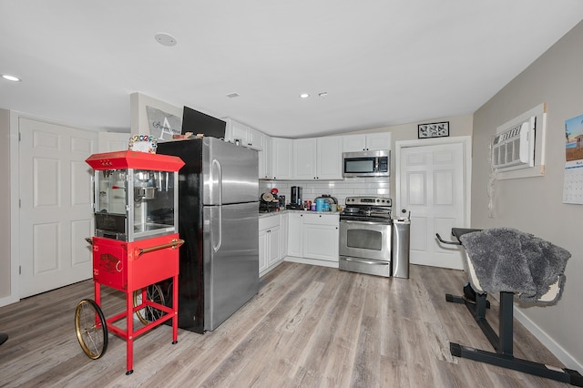 kitchen featuring stainless steel appliances, white cabinetry, baseboards, light wood-style floors, and tasteful backsplash