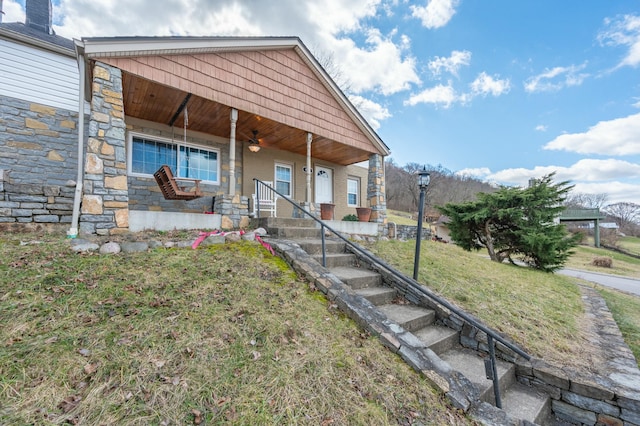 view of front of home featuring a porch, a front yard, and stone siding