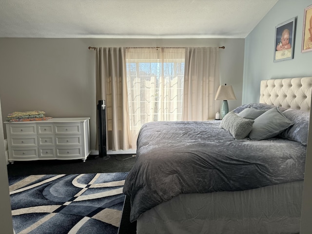 bedroom with dark carpet and a textured ceiling