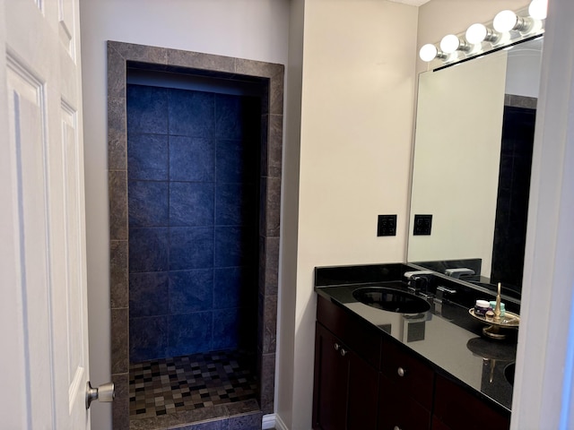 full bathroom with double vanity, tiled shower, and a sink