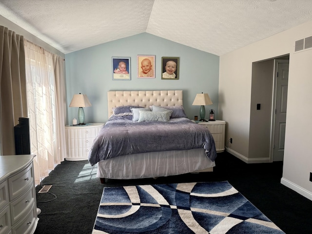 bedroom with vaulted ceiling, visible vents, dark colored carpet, and a textured ceiling