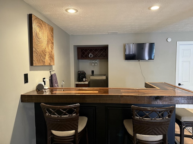 bar with wet bar and a textured ceiling