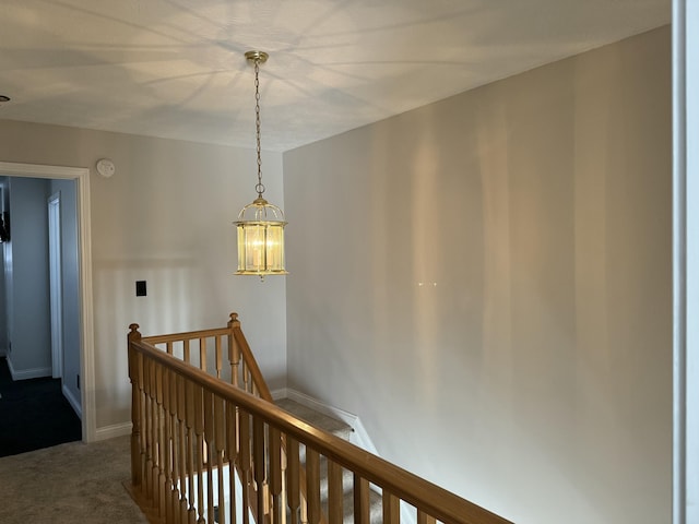 hallway with baseboards, an upstairs landing, an inviting chandelier, and carpet flooring