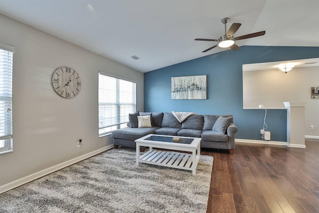 living area featuring dark wood-style floors, visible vents, baseboards, ceiling fan, and vaulted ceiling